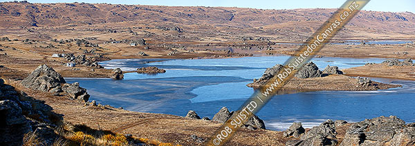 Photo of Poolburn reservior frozen in winter. Fishing baches and cribs around edge. Lord of the Rings location Rohan. Panorama, Ida Burn Valley, Central Otago, Otago Region, New Zealand (NZ)
