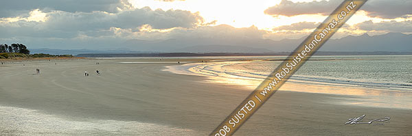 Photo of Tahunanui Beach with people enjoying walking in the evening, with Arthur Range and Kahurangi National Park beyond. Panorama, Nelson, Nelson City, Nelson Region, New Zealand (NZ)