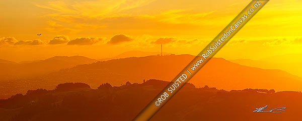Photo of Mt Kaukau and transmitter towers silhouetted at sunset. Aircraft landing into Wellington and wind turbines in distance. Horokiwi in foreground. Seen from North east. Panorama, Belmont, Wellington City, Wellington Region, New Zealand (NZ)