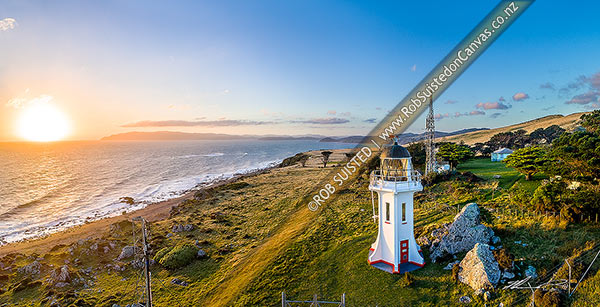 Photo of Baring Head Lighthouse and associated buildings at sunset. Fitzroy Bay and Wellington Harbour entrance behind. Aerial panorama. East Harbour Regional Park, Baring Head, Hutt City, Wellington Region, New Zealand (NZ)