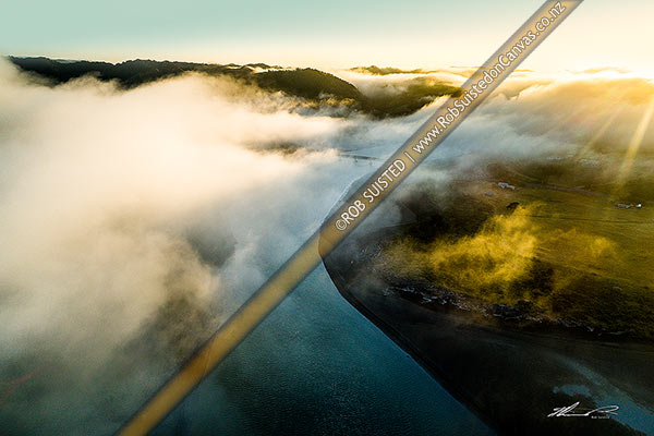 Photo of Mokau River estuary and Mokau River SH3 bridge in morning mist as cold air travels towards the coast. Moody misty sunrise. Aerial view. North Taranaki, Mokau, Waitomo, Waikato Region, New Zealand (NZ)