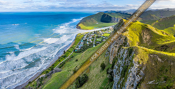 Photo of Kairakau Beach village nestled under coastal escarpment cliffs, on the Mangakuri River mouth. Aerial panorama looking south, Kairakau Beach, Central Hawkes Bay, Hawke's Bay Region, New Zealand (NZ)