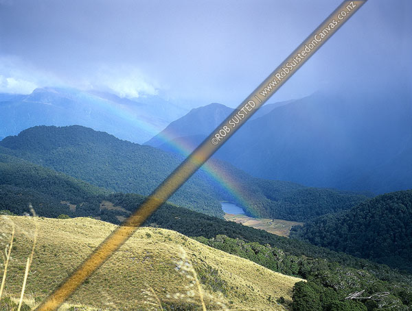 Photo of Lakes Bux and Porm nestled in the Thomson Range, above the Arawhata River. Rainbow over lake, South Westland, Westland, West Coast Region, New Zealand (NZ)
